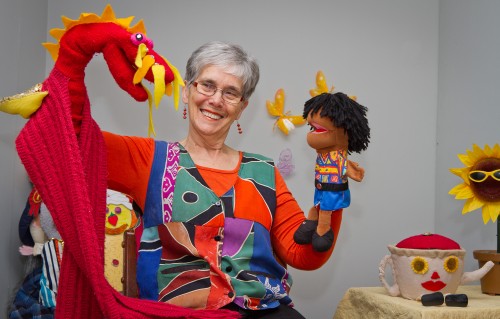 Patsy Allan with some of her favourite puppets, a homemade red dragon based on a character from Chinese folk tale “The Little Rooster and the Heavenly Dragon”, and Sam from her own book “The Boy Who Loved Drums”. Photo by Brent Macdonald