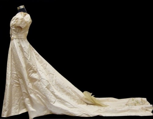 Made specially for an 1890s Liverpudlian industrialist's daughter, who would have mad a dramatic entrance in this duchesse satin gown with its cathedral train.  A touch of lace here, a waist sash, clever pleating and pretty puff sleeves is all this gown needs.  The dramatic train says it all. From the Seams Old Castle Howard Collection