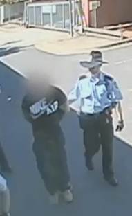 Police arrest the suspected shoplifter in the yard of the Gungahlin Police Station.