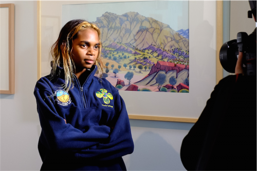 Aretha Namatjira in front of a painting by Kevin Namatjira. Photo by Greer Versteeg 