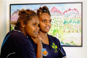 Cheyanne Driffen and Semra White, from Ntaria School, in front of “Tjurretja – West MacDonnell Ranges” by Ntaria School students. Photo by Greer Versteeg 