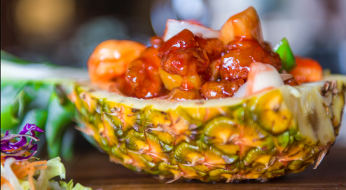 Sweet and sour pork served in a fresh pineapple.